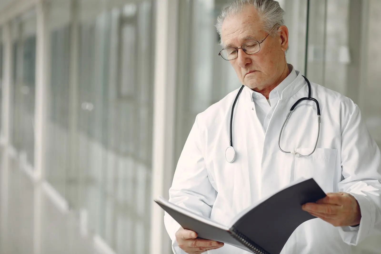 Senior physician in a white coat reading clinical records